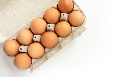 Karton konteynırda nakil için beyaz zemin üzerinde izole edilmiş tavuk yumurtaları. Yukarıdan görüntüle.