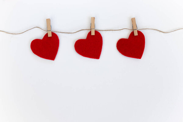 White background with three red hearts on clothespins. Valentine's day card.