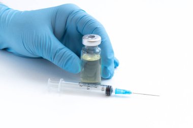 Mavi eldivenli Doktor Eli şişeyi aşıyla ya da beyaz arka planda uyuşturucuyla tutuyor. Coronavirus aşısı çalışma konsepti.