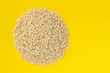 Sarı arka planda izole edilmiş beyaz susam tohumları. Üst görünüm.