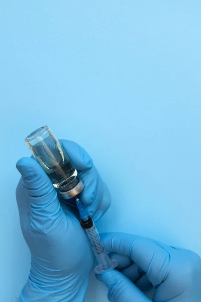 Ręka Lekarza Trzymająca Butelkę Lekiem Strzykawkę Dla Pacjenta Niebieskim Tle — Zdjęcie stockowe