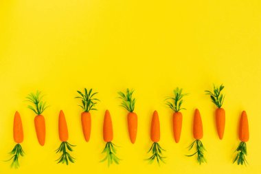 Parlak sarı arka planda havuçla yapılan Paskalya deseni. Minimum Paskalya kompozisyonu. Düz yatıyordu.