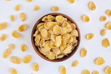 Tahta kase ve mısır gevreği, beyaz arka planda izole edilmiş. Mısır gevrekleri fincanın etrafına dağıldı. Yukarıdan görüntüle.