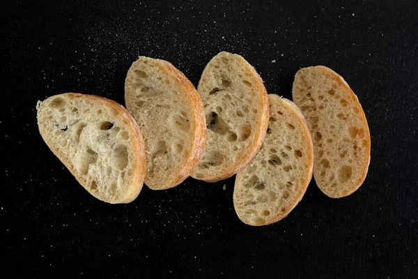 Siyah kırsal arka planda dilimlenmiş ciabatta ekmeği. İtalyan beyaz ekmeği. Üst görünüm
