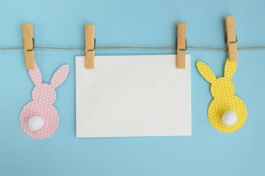 Renkli paskalya kartı ve mavi arka planda Paskalya tavşanı ve boş kartla süslenmiş çelenk. Renkli tatil dekorasyonu üst görünümü