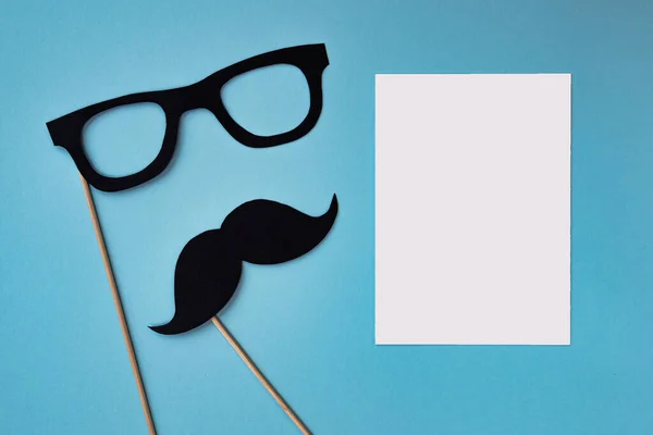 happy father day, composition of black mustache and glasses on blue background, greeting card with white sheet of paper and place for text