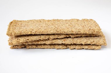 heap of light brown multigrain rye crispbreads isolated on white background, bread cracker snacks, side view