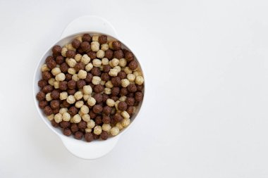 Beyaz arka planda izole edilmiş çikolata ve vanilya gevreği kasesi, çikolata topları, sağlıklı kahvaltı.