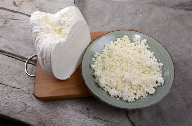 Ahşap bir masa kaşık beyaz bir kase taze peynir.