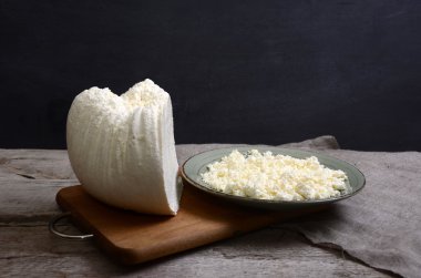 Ahşap bir masa kaşık beyaz bir kase taze peynir.