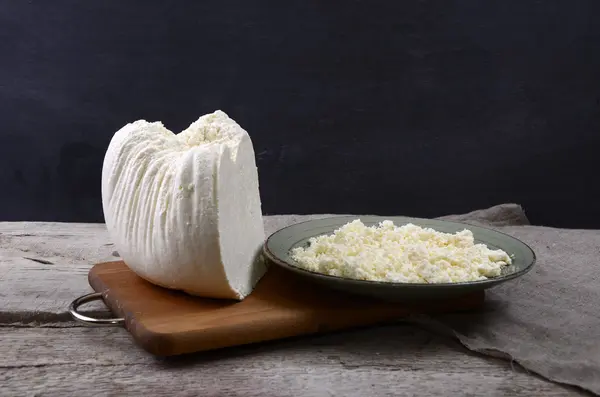 Ricotta fresca in una ciotola bianca con cucchiaio su un tavolo di legno . — Foto Stock