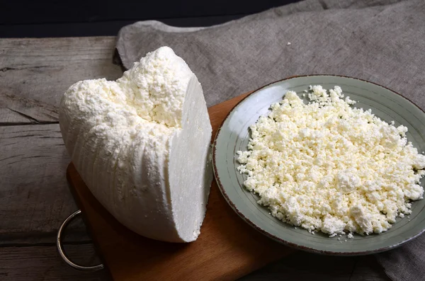 Ahşap bir masa kaşık beyaz bir kase taze peynir.