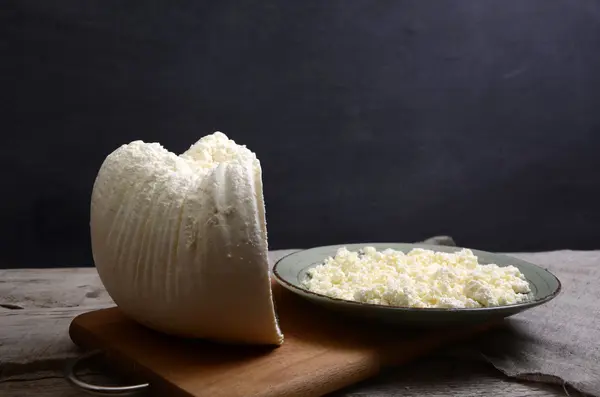 Ricotta fresca in una ciotola bianca con cucchiaio su un tavolo di legno . — Foto Stock