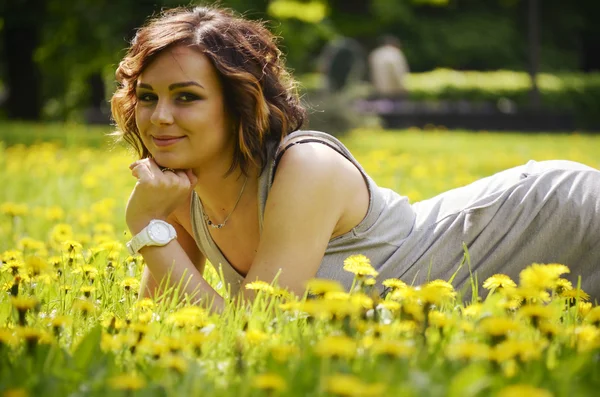 Junge hübsche Frau, die bei Sonnenuntergang im Gras liegt. Natürliches Glück, Spaß und Harmonie. — Stockfoto