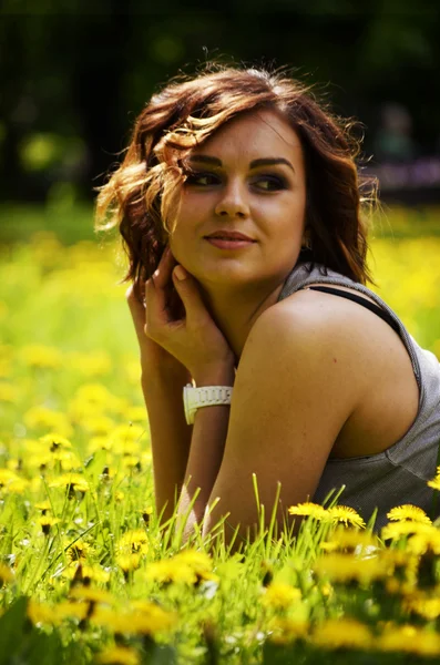 Junge hübsche Frau, die bei Sonnenuntergang im Gras liegt. Natürliches Glück, Spaß und Harmonie. — Stockfoto