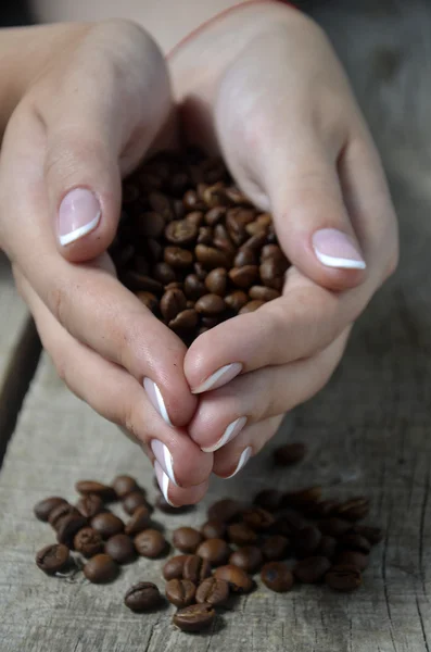 Granos de café en manos sobre fondo de madera — Foto de Stock