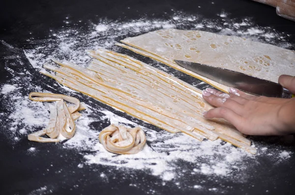 Een jonge vrouw kneedt pasta deeg met de hand — Stockfoto