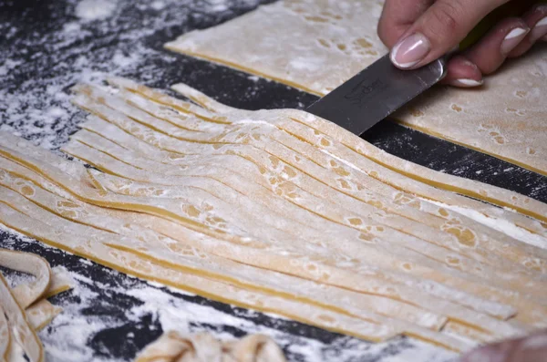 Een jonge vrouw kneedt pasta deeg met de hand — Stockfoto