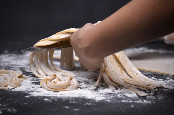 En ung kvinna knådar pasta degen för hand — Stockfoto