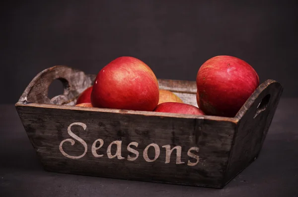 Äpfel in einem Holzkorb, der auf einem hölzernen Hintergrund liegt — Stockfoto