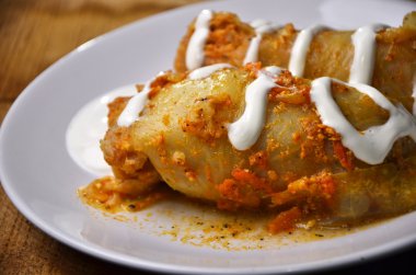 Lahana yaprakları lahana dolması etli plaka üzerinde bir peçete, domates, maydanoz ve sarımsak soluk ahşap tahta bir arka plan üzerine domates sosu