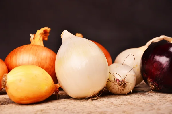 Colorful onions on rustic wooden background — Stock Photo, Image