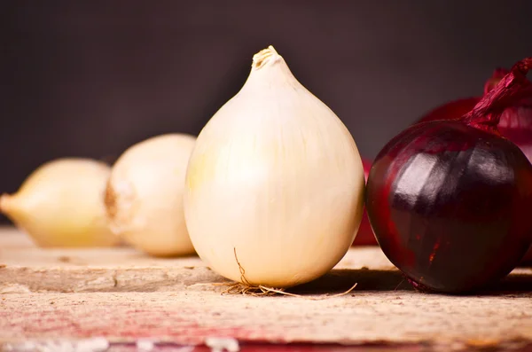 Bunte Zwiebeln auf rustikalem Holzgrund — Stockfoto