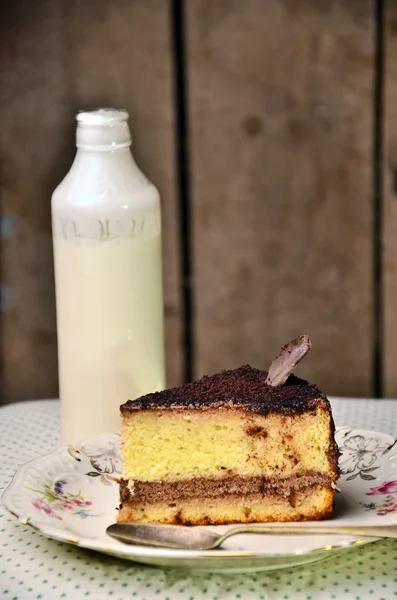 Вкусный сладкий кусок пирога и бутылку молока на скатерти горошек точка — стоковое фото