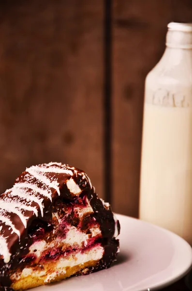 Stück Kuchen mit der Flasche Milch auf der Tischdecke — Stockfoto