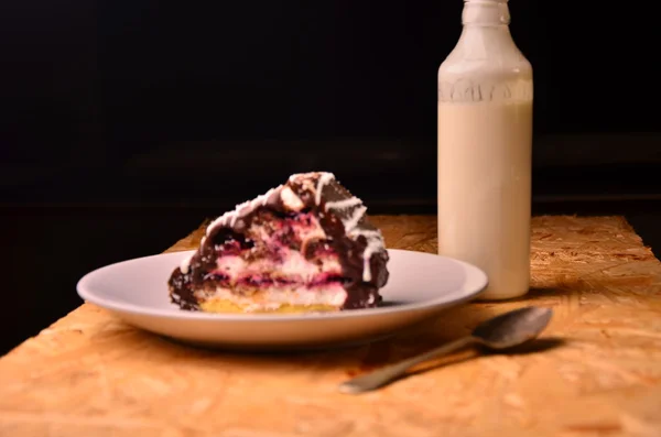 Pedaço de bolo com a garrafa de leite na toalha de mesa — Fotografia de Stock