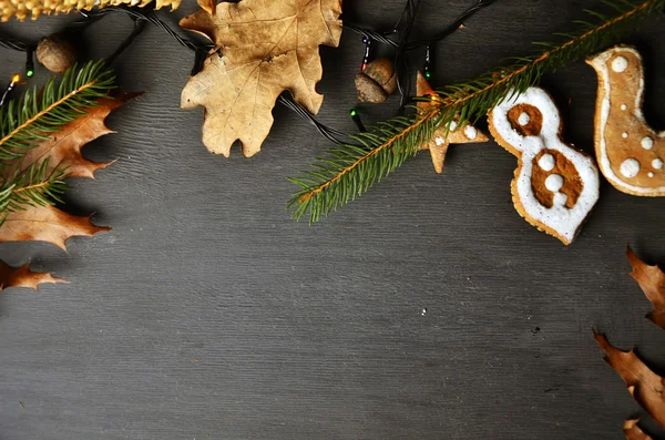 Fondo navideño con decoraciones de hojas otoñales ramas de árbol y galletas en pizarra de madera — Foto de Stock