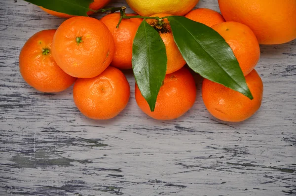 Tangerines with leaves in Christmas decor with Christmas tree, dry orange and candies over gray plaster surface. Top view. — Stock Photo, Image