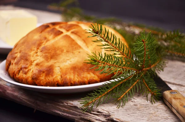 Pão caseiro fresco está deitado em um prato branco em uma mesa de madeira ao lado de um prato com o comprador. Natal. — Fotografia de Stock