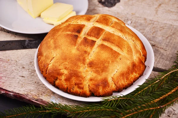 Pão caseiro fresco está deitado em um prato branco em uma mesa de madeira ao lado de um prato com o comprador. Natal. — Fotografia de Stock