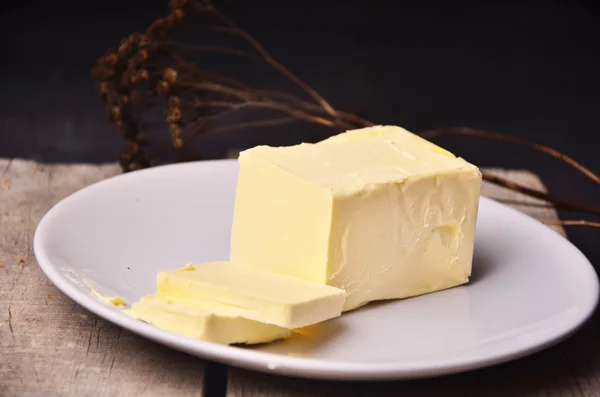 Pat bir bıçak ile bir tereyağı yemek üzerine taze çiftlik tereyağı yaymak veya cooing madde, çıtalı ahşap bir masa üzerinde havai görünümü kullanın — Stok fotoğraf