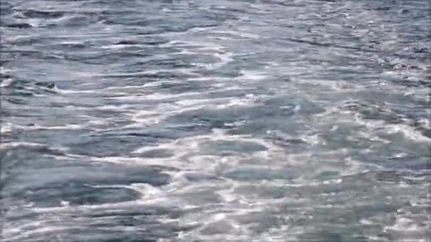 Синя морська вода, що проходить з рухомого човна з блискітками та світловими відображеннями — стокове відео