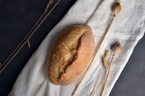 Čerstvý chléb a rohlíky s uši pšenice na stůl — Stock fotografie