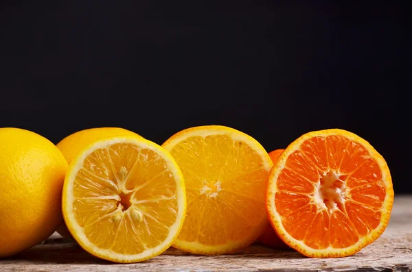 Крупный план кучи нарезанных апельсинов и свежего апельсинового сока на деревянном фоне. Кадр для еды. Свободное место для текста — стоковое фото
