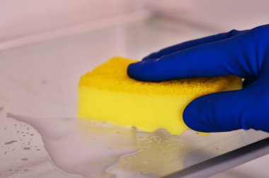 Kadın eli mavi kauçuk koruyucu eldiven sarı bez ile temizlik beyaz açık boş buzdolabı. Temizlik kavramı. Temiz