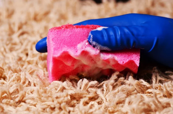 Mensen, huishoudelijk werk en huishouden concept - close up van vrouw in rubber handschoenen met doek en detergenten spray schoonmaak tapijt thuis — Stockfoto