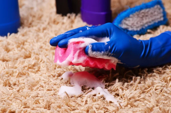 Mensen, huishoudelijk werk en huishouden concept - close up van vrouw in rubber handschoenen met doek en detergenten spray schoonmaak tapijt thuis — Stockfoto