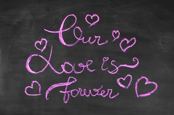 我们的爱是永远。粉红色的粉笔在黑板上画。情人节那天的背景. — 图库照片