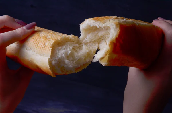Brood stokbrood in zijn hand op een witte achtergrond — Stockfoto