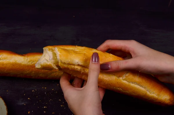 Bolsita recién horneada en rodajas en una bandeja para cortar pan de madera. Hay una segunda barra de pan en el fondo . — Foto de Stock