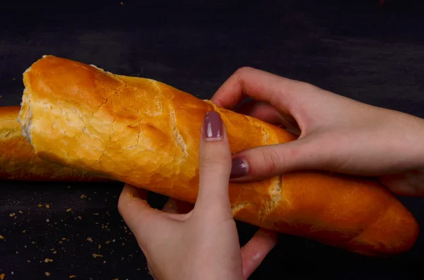 Čerstvě upečený bagette plátky na plech řezání dřevěných chleba. Je tu druhý bochník chleba na pozadí. — Stock fotografie