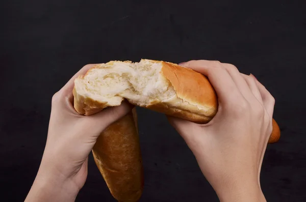 Brood stokbrood in zijn hand op een witte achtergrond — Stockfoto