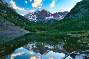 Sunset 'te Aspen Colorado' da kestane rengi çanlar. Güzel kestane rengi ve camdan yansıyan pembe bulutlar. Kayalıklar ve ağaçlar arasında çerçevelenmiş sudaki dağların yansıması