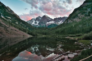 Sunset 'te Aspen Colorado' da kestane rengi çanlar. Güzel kestane rengi ve camdan yansıyan pembe bulutlar. Kayalıklar ve ağaçlar arasında çerçevelenmiş sudaki dağların yansıması