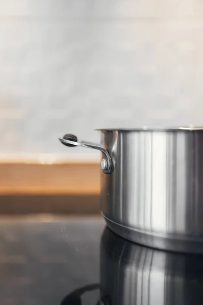 Premium AI Image  Steaming and boiling pan of water on modern heating  stove in kitchen on the background of open balcony Boiling with steam  emitted from stainless cooking pot