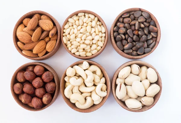 Zes soorten noten in een ronde houten vorm (amandelen, hazelnoten, pijnboompitten, cashewnoten, pistache) — Stockfoto